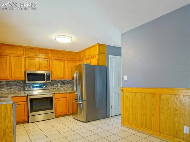 a kitchen with stainless steel appliances granite countertop a refrigerator and a stove top oven