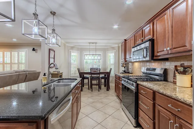 a kitchen with stainless steel appliances granite countertop a sink a stove and a wooden cabinets