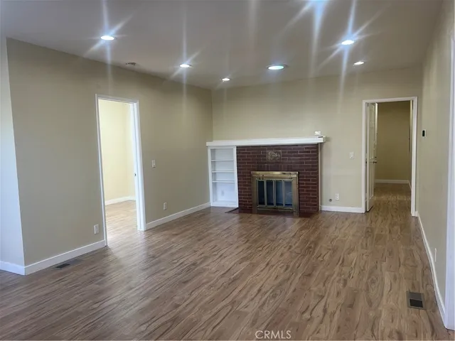 an empty room with wooden floor and fireplace