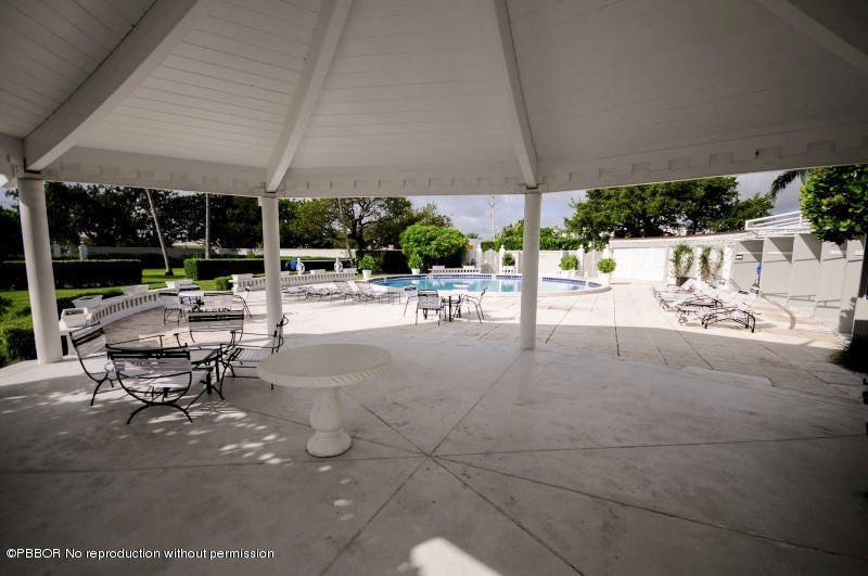 2185 Ibis Isle Road, Unit 2 Palm Beach, FL 33480 - Photo 23 of 26 a view of a patio with a table and chairs under an umbrella next to a yard