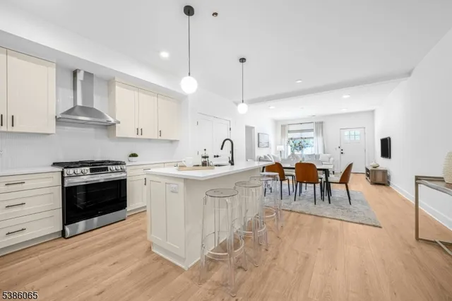 a kitchen with stainless steel appliances kitchen island granite countertop a stove a sink a dining table and chairs with wooden floor