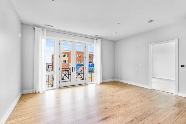 a view of an empty room with window and wooden floor