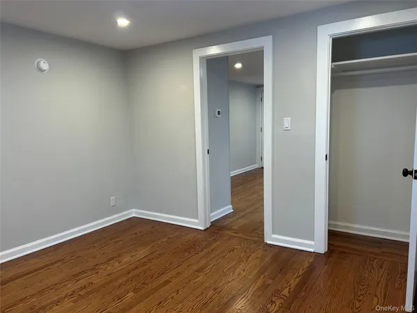 a view of an empty room with wooden floor and closet