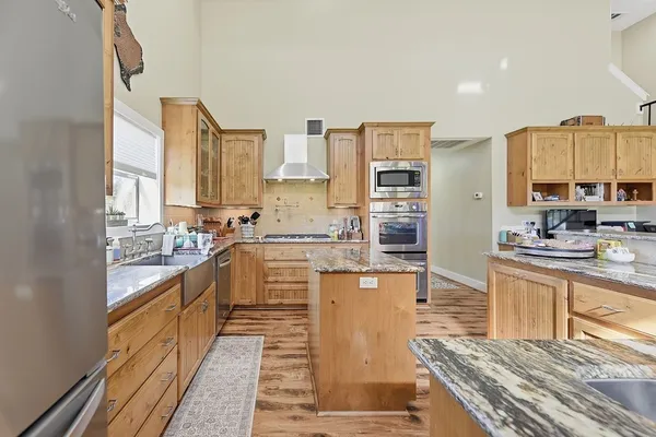 a large kitchen with kitchen island granite countertop a stove top oven a sink and white cabinets