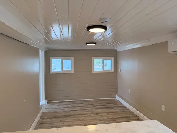 an empty room with wooden floor chandelier fan and windows