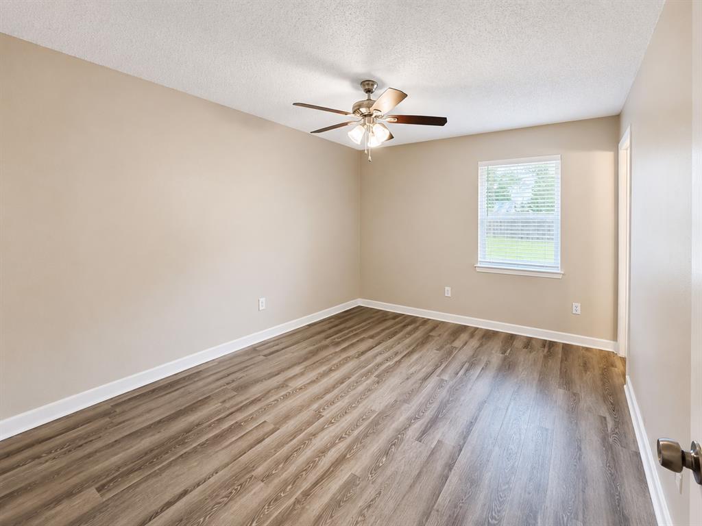 1231 Rutherford Drive Mesquite, TX 75149 - Photo 8 of 29 an empty room with wooden floor fan and windows