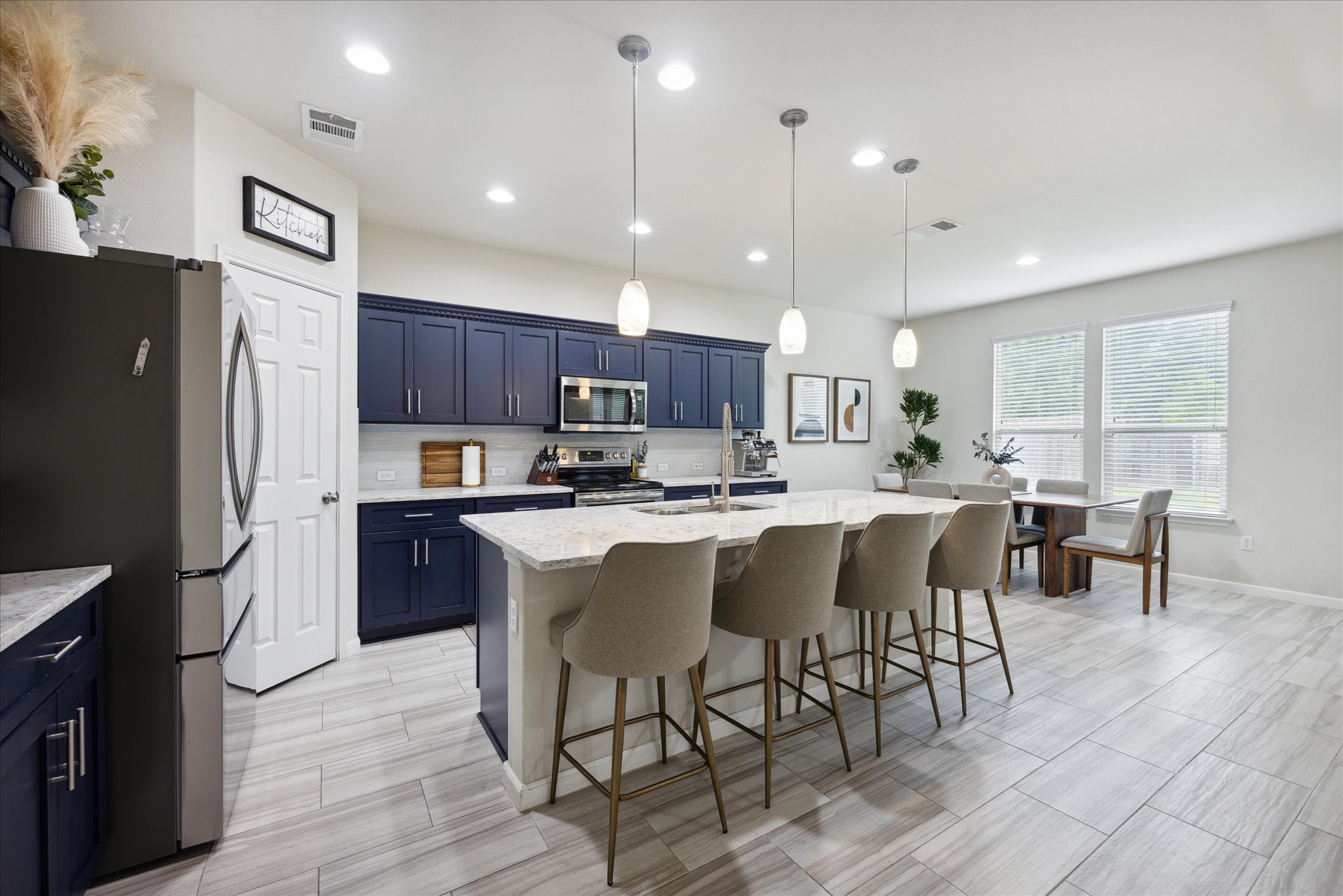a kitchen with stainless steel appliances granite countertop a refrigerator a stove top oven a sink dishwasher a dining table and chairs with wooden floor