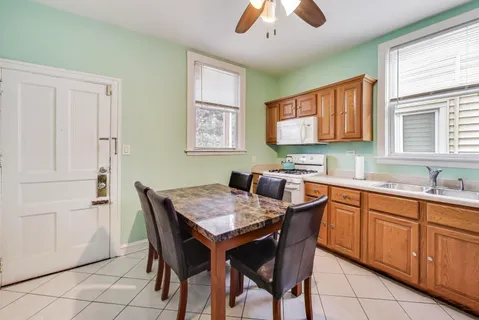a kitchen with stainless steel appliances granite countertop a dining table chairs and a refrigerator