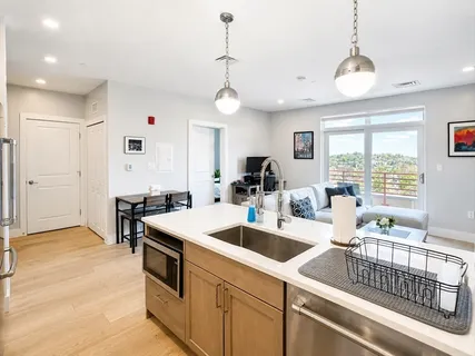 a kitchen that has a sink a stove and a dining table with white cabinets