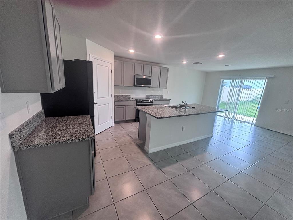 6730 Southeast 3rd Loop Ocala, FL 34472 - Photo 3 of 16 a kitchen with stainless steel appliances granite countertop a sink and a refrigerator