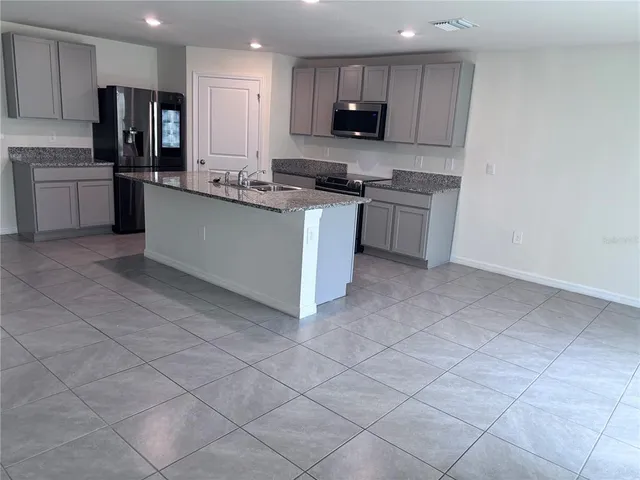 a kitchen with stainless steel appliances granite countertop a stove top oven a sink and a refrigerator