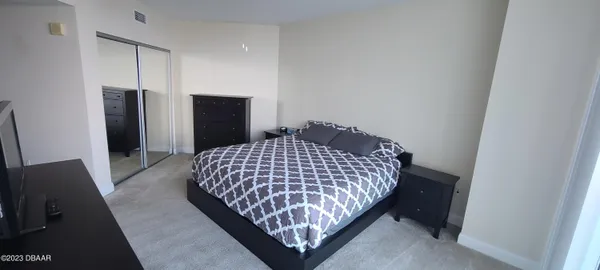 a bedroom with a bed and a flat tv screen on a dresser