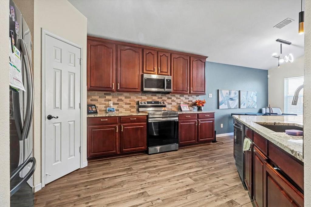 1412 Cheyenne Road Wylie, TX 75098 - Photo 12 of 24 a kitchen with stainless steel appliances granite countertop a stove a sink dishwasher a refrigerator and a oven with wooden floor
