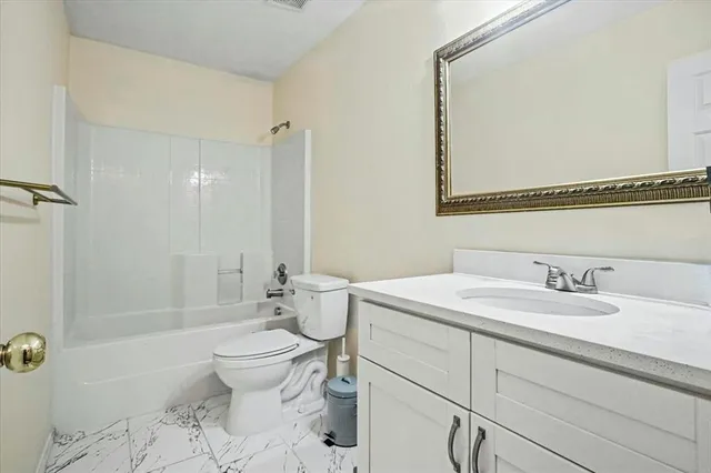 a bathroom with a granite countertop toilet a sink and a mirror