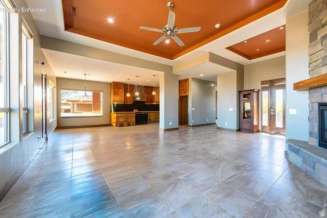322 340 E Street Ivins, UT 84738 - Photo 10 of 61 Spacious interior featuring large format tile flooring, a stone-front fireplace with a wood mantle, a tray ceiling with a ceiling fan, and double entry doors with glass inserts