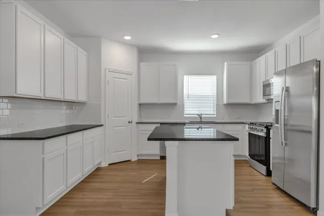 a kitchen with stainless steel appliances granite countertop a sink a stove a refrigerator and cabinets