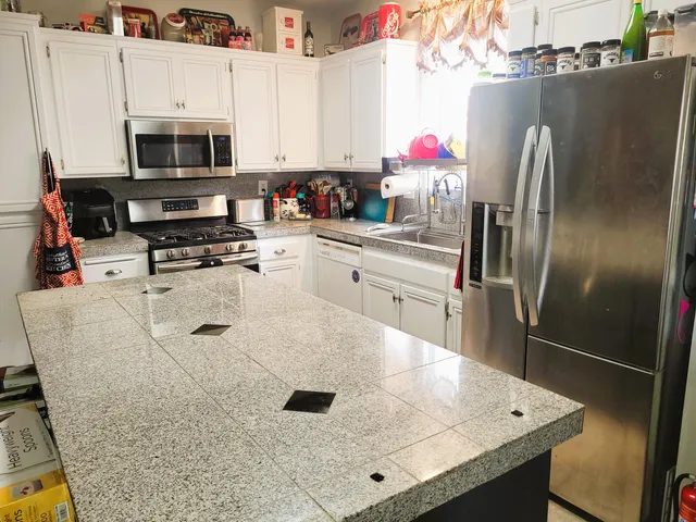 a kitchen with stainless steel appliances granite countertop a refrigerator a stove and a sink with wooden floor