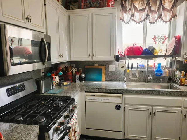 a kitchen with stainless steel appliances granite countertop a stove a sink and a microwave