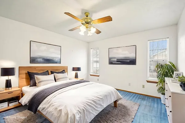 an empty room with wooden floor fan and windows