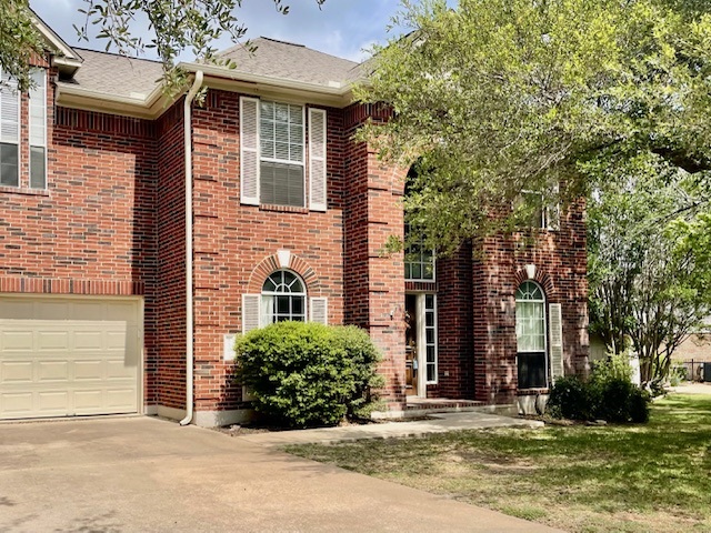 View of front of home with an attached garage, driveway, brick siding, and a shingled roof