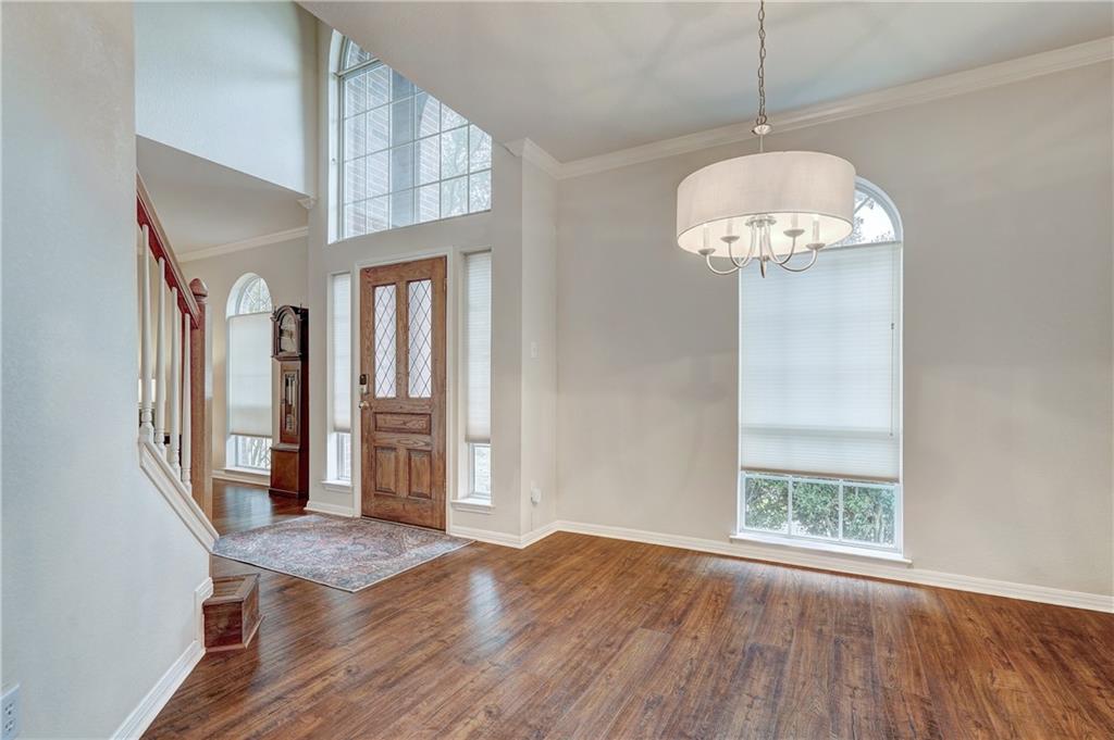 8504 Ephraim Road Austin, TX 78717 - Photo 3 of 16 Entrance foyer featuring crown molding, dark wood-style flooring, a high ceiling, healthy amount of natural light, and hanging lights
