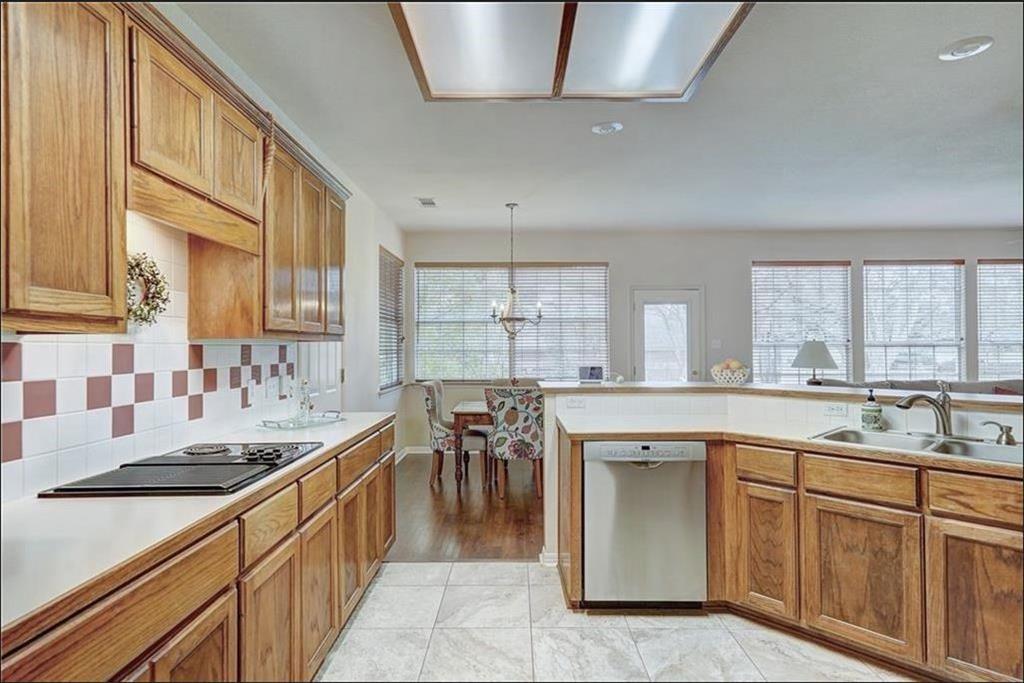 8504 Ephraim Road Austin, TX 78717 - Photo 6 of 16 Kitchen with light countertops, dishwasher, hanging light fixtures, and wood finish cabinets