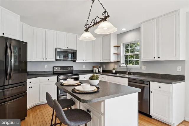 a kitchen with a sink a stove a refrigerator cabinets and dining table