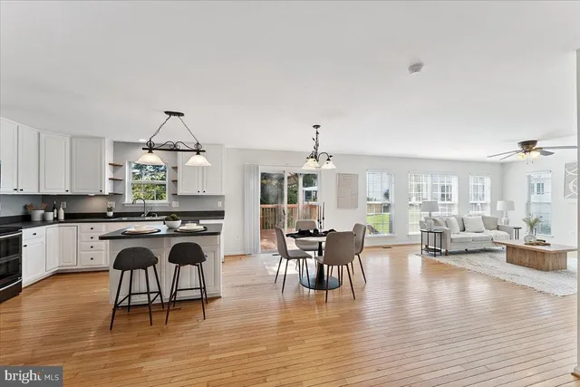 a kitchen with stainless steel appliances granite countertop a stove top oven a refrigerator a sink dishwasher a dining table and chairs with wooden floor