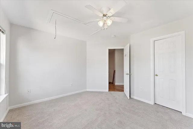 an empty room with windows and ceiling fan