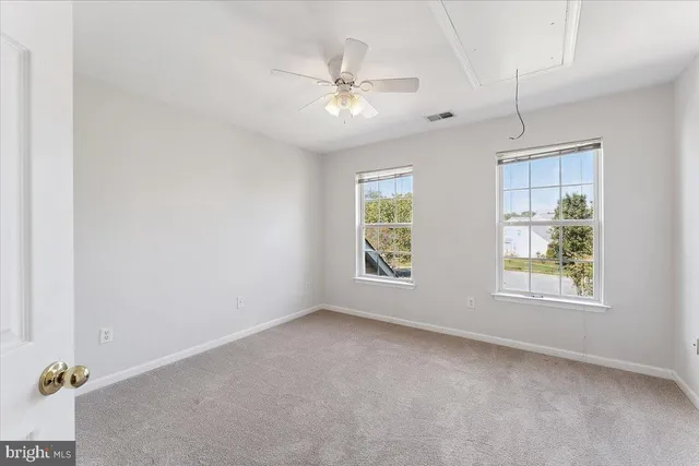 a view of an empty room with a window and a kitchen