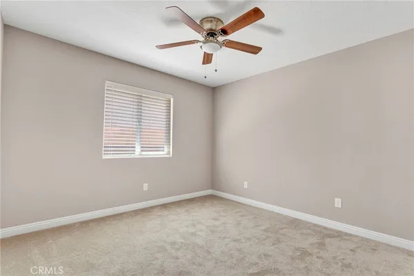 an empty room with windows and ceiling fan