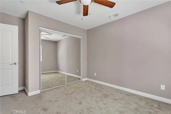 an empty room with a ceiling fan and carpet