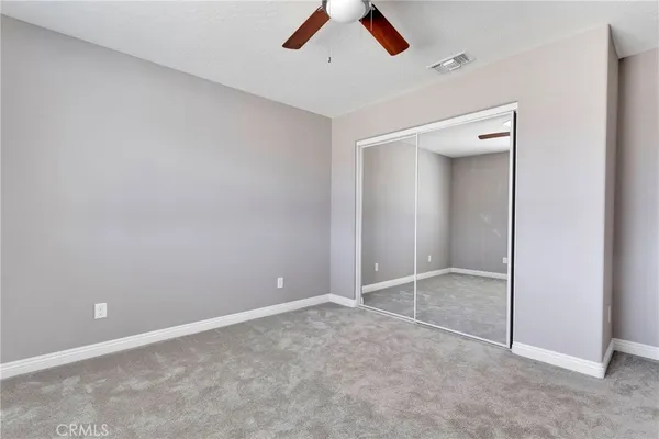 an empty room with closet and a chandelier fan