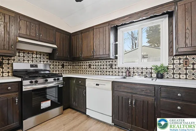a kitchen with stainless steel appliances granite countertop a stove a sink dishwasher and cabinets with wooden floor