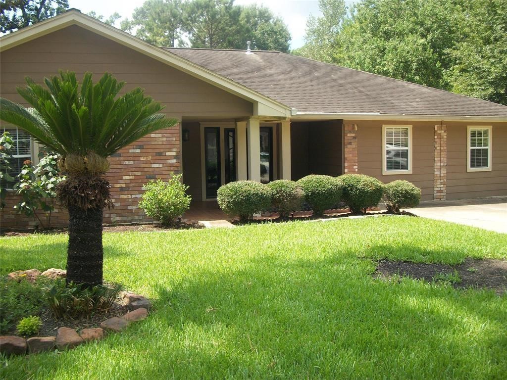 111 Shadylyn Drive Conroe, TX 77304 - Photo 1 of 18 a house that has a yard plants and large tree