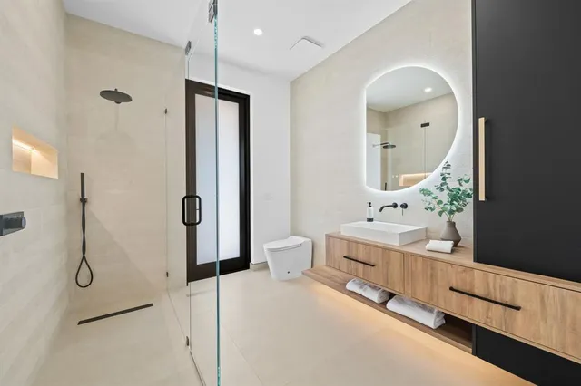 a spacious bathroom with a double vanity sink toilet mirror and shower