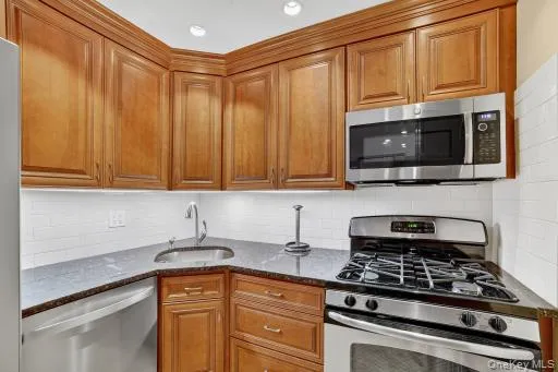 a kitchen with stainless steel appliances granite countertop a stove top oven a sink dishwasher and cabinets with wooden floor