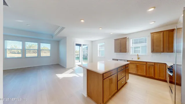 a large kitchen with stainless steel appliances a large counter top a stove a refrigerator a sink a center island and couches