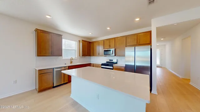 a kitchen with stainless steel appliances a sink a stove a refrigerator a microwave a sink and cabinets