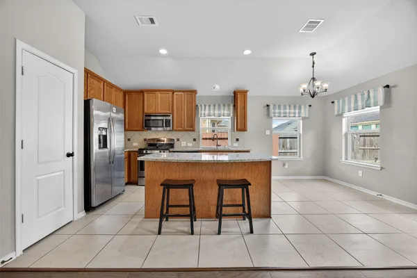 a kitchen with stainless steel appliances granite countertop a refrigerator a sink a stove and a cabinets