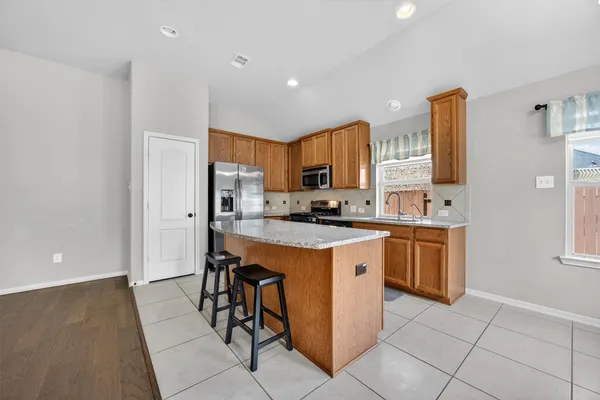 a kitchen with stainless steel appliances granite countertop a stove top oven a sink a refrigerator and a island