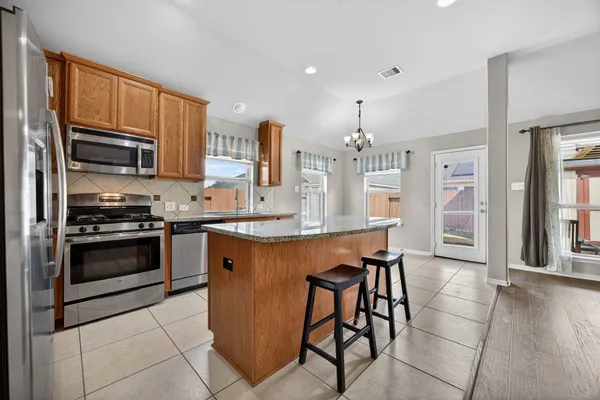a kitchen with stainless steel appliances kitchen island granite countertop a stove a sink and a microwave