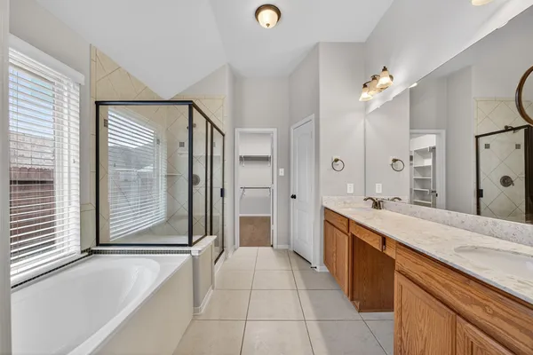 a large bathroom with a tub sink vanity and a mirror