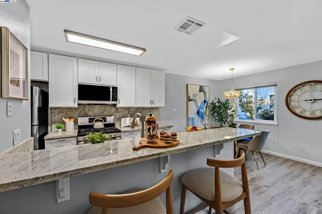 a kitchen with granite countertop a sink chairs and microwave