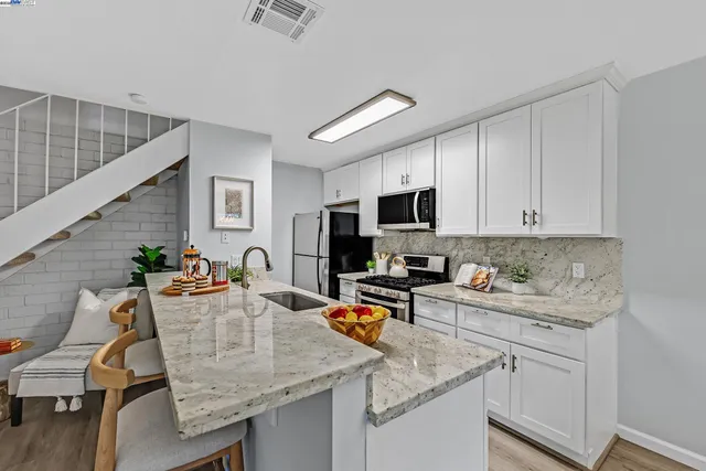 a kitchen with stainless steel appliances granite countertop a sink dishwasher stove refrigerator and microwave with wooden floor