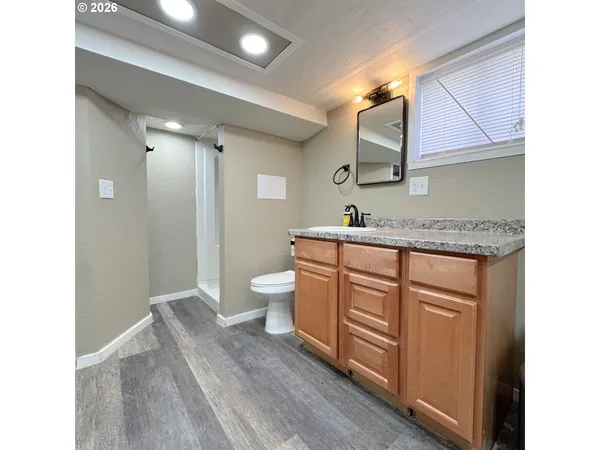 a bathroom with a granite countertop sink mirror and a toilet