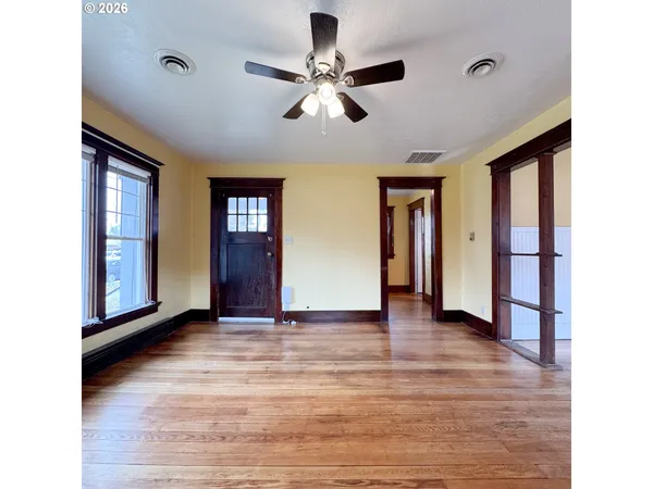 a view of an empty room with window and wooden floor