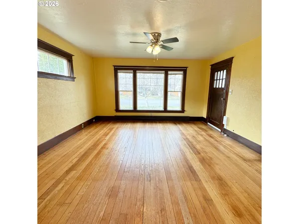 a view of an empty room with wooden floor and a window