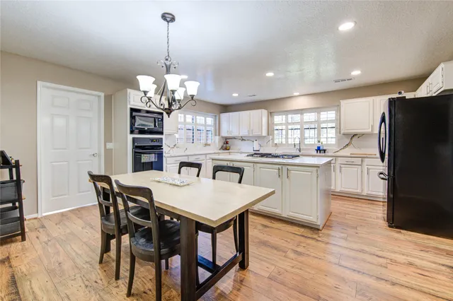 a kitchen with stainless steel appliances kitchen island granite countertop a table chairs and a refrigerator