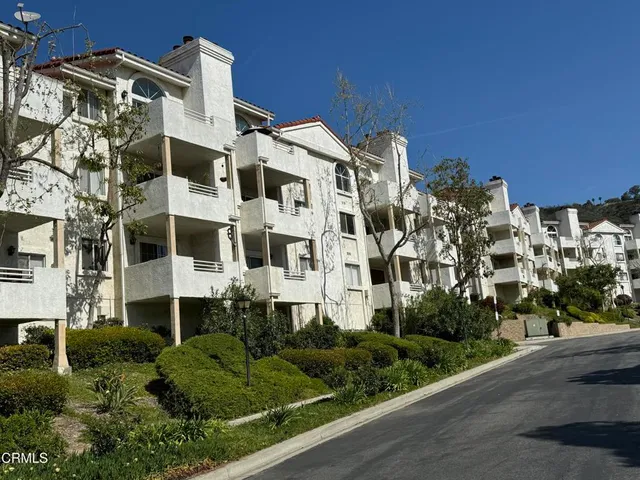 a view of a building with a yard and large trees